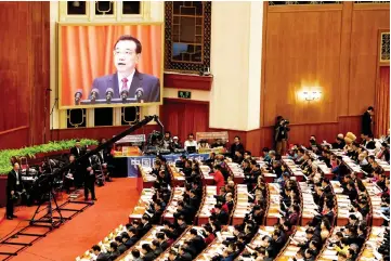  ?? — AFP photo ?? Li is shown on a screen as he delivers his work report during the opening session of the National People’s Congress in Beijing’s Great Hall of the People.