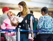  ?? (AP FOTO) ?? SCREEN TIME WITH MOMMY. In this Friday, Sept. 26, 2014, file photo, Ann Walden checks her phone as 15-month-old daughter Delphine plays while waiting in line after their flight to Baton Rouge was delayed at O’Hare Internatio­nal Airport in Chicago.