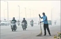  ??  ?? A civic worker, wearing an anti-pollution mask, sweeps the road amid heavy smog, in New Delhi on Friday.