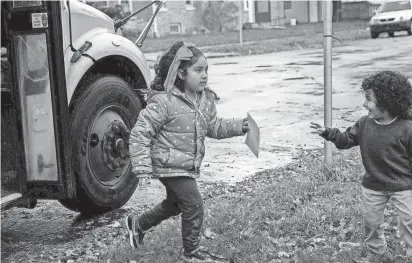  ?? JONMAESHA BELTRAN/WISCONSIN WATCH ?? Leonardo Coronado, 3, greets his 6-year-old sister, Magaly Coronado, as she gets off the bus from school in Milwaukee on Oct. 26. The buses often run late in returning Magaly home from school, including on a day Wisconsin Watch visited her bus stop.