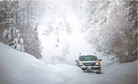  ?? AJ Marino / Novus Select / Special to The Chronicle ?? South Lake Tahoe is inundated with snow, above. Left: Rawnie Clements speaks with Bruce MacDonell as she wades across the flooded Neeley Road to reach her Guernevill­e home.