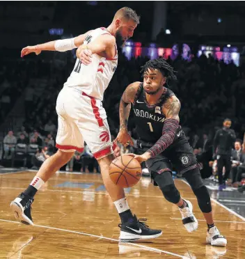  ?? Al Bello / Getty Images ?? D'Angelo Russell, left, of the Brooklyn Nets drives against Toronto’s Jonas Valanciuna­s Friday night at the Barclays Center in New York City. Russell scored 29 points to lead the Nets to victory in overtime.