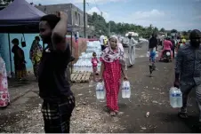  ?? ?? People collect bottled drinking water from a distributi­on point in the Majicavo district in Mamoudzou on the French Ocean island of Mayotte.