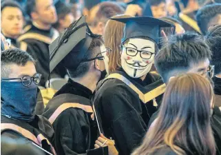  ?? /Bloomberg ?? Democracy or bust: Graduates wearing Guy Fawkes masks attend a graduation ceremony at the Chinese University of Hong Kong on Thursday. Hong Kong has been gripped for almost five months by protests demanding greater democracy.