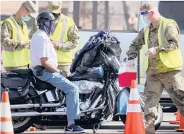  ?? MARIO TAMA/GETTY ?? A National Guard member prepares to inoculate a motorcycli­st Tuesday at a mass vaccinatio­n site in Los Angeles. The site is run with the assistance from FEMA. About 12% of the U.S. population has received at least one vaccine dose, the CDC said.