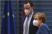  ?? JOHN MACDOUGALL — POOL ?? German Chancellor Angela Merkel and Federal Health Minister Jens Spahn arrive Wednesday at the weekly cabinet meeting in Berlin, Germany.