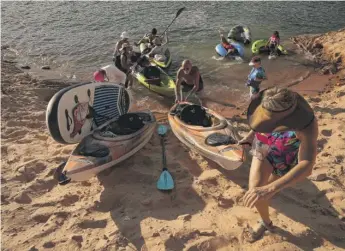  ?? BRITTANY PETERSON/AP ?? Tourists carry a kayak up a sandy hill in Page, Arizona. While Lake Powell levels drop, recreation is becoming tougher to access as boat ramps and marinas close.