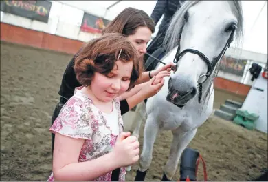  ?? LIANG SEN / XINHUA ?? A blind child pets a horse with the help of a circus performer in Vancouver, Canada, on Thursday.