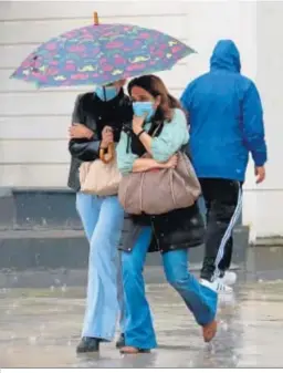  ??  ?? Dos mujeres comparten paraguas por la capital.