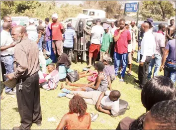  ??  ?? Over a dozen commuters cheated death when a kombi they were travelling in overturned along Robert Mugabe Road near the Vehicle Inspection Department’s Eastlea depot yesterday morning. Here, the injured await the arrival of an ambulance to ferry them to the hospital. — (Picture by Nicholas Bakili)