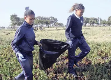  ?? PICTURES: JILL WILLIAMS ?? CLEANING UP: Robin Tromp and Sasha-Lee Dysan from Levana Primary School in Lavender Hill clear litter from the banks of Princess Vlei, before getting down to some serious gardening. Pupils filled nine bags of litter.
