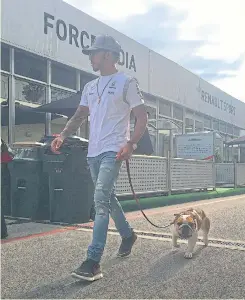  ??  ?? Mercedes’ Lewis Hamilton walks into the paddock with his dog Coco.