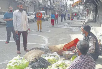  ?? PARDEEP PANDIT/HT ?? People standing on earmarked space to maintain minimum distance (3 feet) while buying vegetables and fruits during curfew in Jalandhar on Thursday.