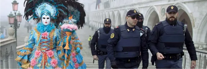  ??  ?? Costumi e uniformi
Gente in maschera vicino a piazza San Marco, in una Venezia super pattugliat­a. Ieri l’annuncio dello stop ai festeggiam­enti del Carnevale che si sarebbe comunque concluso con il Martedì Grasso (Epa)