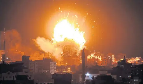  ?? AFP ?? ABOVE A ball of fire is seen above the building housing a Hamas-run television station in Gaza City during an Israeli air strike.