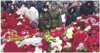  ?? AFP ?? People lay flowers at a makeshift memorial outside the Crocus City Hall in Krasnogors­k on Sunday, as Russia observes a national day of mourning after a massacre that killed more than 130 people.