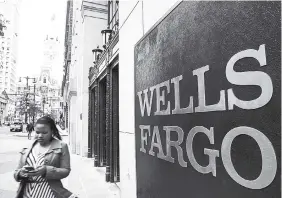  ?? AP ?? A woman walks past a Wells Fargo location in view of City Hall (left) in Philadelph­ia, Thursday, May 11, 2017.