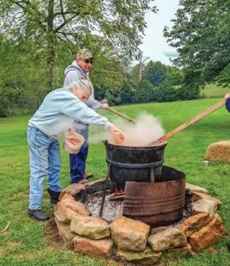  ??  ?? Clockwise from left: Andy Pittman stirs the bubbling apple mixture while his cousin Helen Cunningham adds some cinnamon; picking apples is part of the fun; apples go into the press for cider.