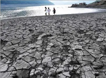  ?? AFP ?? People walk along the dried and cracked river beach of the Yangtze River in Yunyang county in Chongqing, China, on August 24.