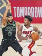  ?? Kevin C. Cox / Getty Images ?? Jimmy Butler of the Heat drives against Jayson Tatum of the Celtics on Thursday. Butler had 14 points.