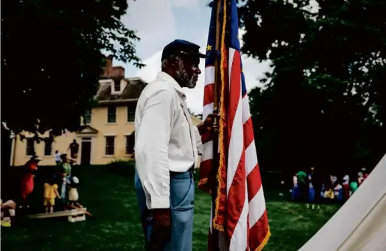  ?? ?? Joe Zellner, of the 54th Massachuse­tts Infantry, held the United States flag at Lexington’s Quock Walker Day celebratio­n.