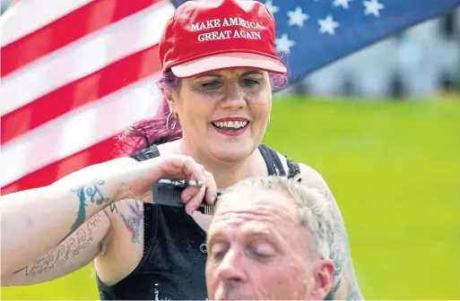  ?? JASON REDMOND AFP/GETTY IMAGES FILE PHOTO ?? Laina Moore gives a haircut on the state capitol lawn in Olympia, Wash., this month to protest stay-at-home orders. No matter their political persuasion, Americans may well agree there are deep wounds in U.S. society, Edward Keenan writes. Agreement on the path to recovery, however, will no doubt be difficult to achieve.