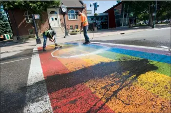  ?? @IMartensHe­rald Herald photos by Ian Martens ?? City workers Corbin Karl and Cale Wright clean off the rainbow crosswalk Thursday morning downtown after black paint was splashed across the colours sometime overnight.