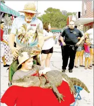  ?? RITA GREENE/MCDONALD COUNTY PRESS ?? Braxton Bishop of Pineville bravely holds Snuggles, a 7-foot-long alligator—one of the stars of the show presented by the Alligator Man, Ken Henderson, at Jesse James Days at Pineville Aug. 10-13. Henderson is placing another alligator, Spike, on...