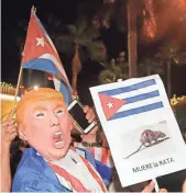  ??  ?? ALAN DIAZ, AP A person in a Donald Trump mask holds a sign that reads “the Rat Dies” in Miami as he celebrates the death of Fidel Castro.