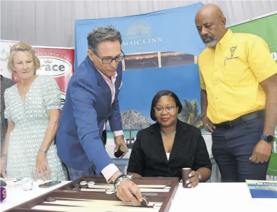  ?? (Photo: Garfield Robinson) ?? Kyle Mais (second left) , managing director at Jamaica Inn Hotel, engages Tisheecka Clarke (second right), analyst, productive sectors at TEF, and Stewart Jacobs, general manager at Arosa Limited, in a game of backgammon during the launch of the fundraisin­g event at the Spanish Court Hotel on Wednesday. At left looking on is Belinda Collier-morrow, co-chair of the White River Fish Sanctuary and a JIF board member.