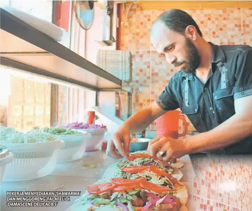  ??  ?? PEKERJA MENYEDIAKA­N ‘SHAWARMA’ DAN MENGGORENG ‘FALAFEL’ DI ‘DAMASCENE DELICACIES’