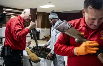  ?? Alexandra Wimley/Post-Gazette ?? Pittsburgh police firearms instructor­s Officer Jim Sippey, left, and Officer Ken Sowinksi, right, take guns surrendere­d by Dereck Hall, of Penn Hills, center, during the Episcopal Church of the Holy Cross' gun buyback on Monday.