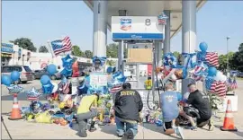  ?? James Nielsen
Houston Chronicle ?? MOURNERS gather at the gas station near Houston to pay their respects at the makeshift memorial to Harris County Sheriff’s Deputy Darren Goforth, 47.