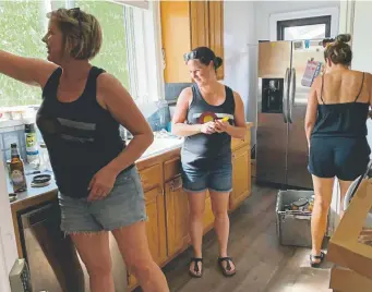  ?? Saja Hindi, The Denver Post ?? Andi Lucas, center, pauses as she works with friends to empty her kitchen during Lucas’ “massive deportatio­n garage sale” at her home in Denver on July 28.