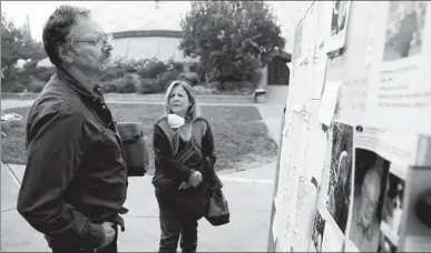  ?? TERRAY SYLVESTER / REUTERS ?? Lane and Julie Walker, of Magalia, look for people they know on a list of those missing in the aftermath of the Camp Fire in Chico, California, on Thursday.