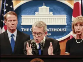  ??  ?? Ohio Gov. Mike DeWine delivers a statement with Lt. Gov. Jon Husted (left) and First Lady Fran DeWine (right) following the Dayton Mass Shooting on Tuesday, at the Ohio Statehouse in Columbus, Ohio. JOSHUA A. BICKEL /THE COLUMBUS DISPATCH VIA AP