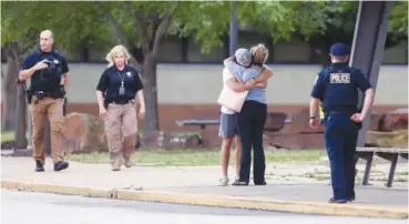  ?? IAN MAULE/TULSA WORLD VIA AP ?? Two people hug outside at Memorial High School where people were evacuated from the scene of a shooting Wednesday at the Natalie Medical Building in Tulsa, Okla.