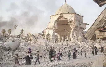  ??  ?? Des civils fuient les combats, en passant devant la mosqué détruite d’Al-Nuri, mardi. − Associated Press: Felipe Dana