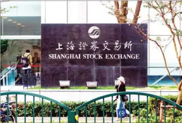  ?? CHINA DAILY ?? A pedestrian passes the Shanghai Stock Exchange in Pudong New Area.