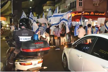  ?? (Israel Police) ?? A POLICE OFFICER keeps an eye on a group of pro-deportatio­n protesters congregati­ng at a south Tel Aviv intersecti­on.