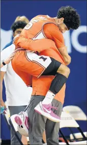  ??  ?? Illinois guard Andre Curbelo jumps into the arms of head coach Brad Underwood at the close of the Illini’s win over Michigan.