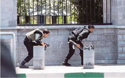  ?? REUTERS PIC ?? Members of Iranian security forces taking cover during an attack on Iran’s Parliament in Teheran yesterday.