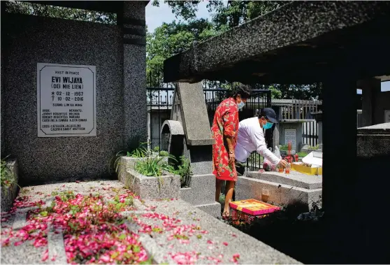  ?? DIPTA WAHYU/JAWA POS ?? TABUR BUNGA KE MAKAM: Samandra (baju merah), warga Surabaya, sedang berdoa dan memberikan sesajen di pusara keluargany­a sesuai dengan tradisi etnis Tionghoa di makam Kembang Kuning. Kemarin merupakan puncak Ceng Beng.