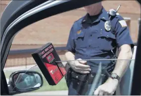  ?? BRAD VEST/THE COMMERCIAL APPEAL ?? Lt. Hal Banks with the Colliervil­le Police Department demonstrat­es a Tint Meter Enforcer, a small device that measures the amount of light that passes through a window.