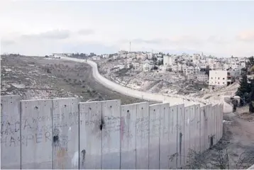  ?? DAN BALILTY/THE NEW YORK TIMES 2020 ?? The Palestinia­n village of Abu Dis, right, sits across Israel’s barrier from east Jerusalem.