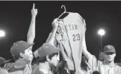  ??  ?? Rattan players hold up the jersey of teammate Brandon Jones, who had already left for Army basic training and could not play in the title game.