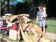  ?? The Associated Press ?? ■ Dave Coughlin carries his 1-year-old son Thomas to their car to get him out of their flood-damaged home in Cranford, N.J., on Saturday. His home, like many others impacted by the remnants of Tropical Storm Ida, has sewage in the basement that needs to be cleaned out.