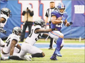  ?? Seth Wenig / Associated Press ?? The New York Giants’ Saquon Barkley is tackled by the Jacksonvil­le Jaguars’ Telvin Smith during the second half on Sept. 9.