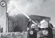  ?? SYRIAN CIVIL DEFENSE WHITE HELMETS VIA AP ?? Civil Defense workers extinguish a fire in a house following airstrikes Saturday in Maarat al-Nuaman, Syria.