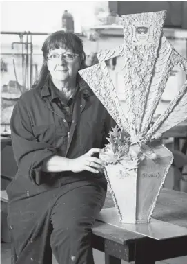  ?? Tijana Martin/calgary Herald ?? Diane M. Anderson with the trophy she has sculpted in brass for the Shaw Charity Classic. The native Calgarian says the 42-inch-high trophy weighs about 60 pounds.